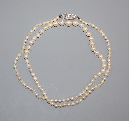 A single strand graduated cultured pearl necklace with diamond three-stone and platinum clasp 46cm.